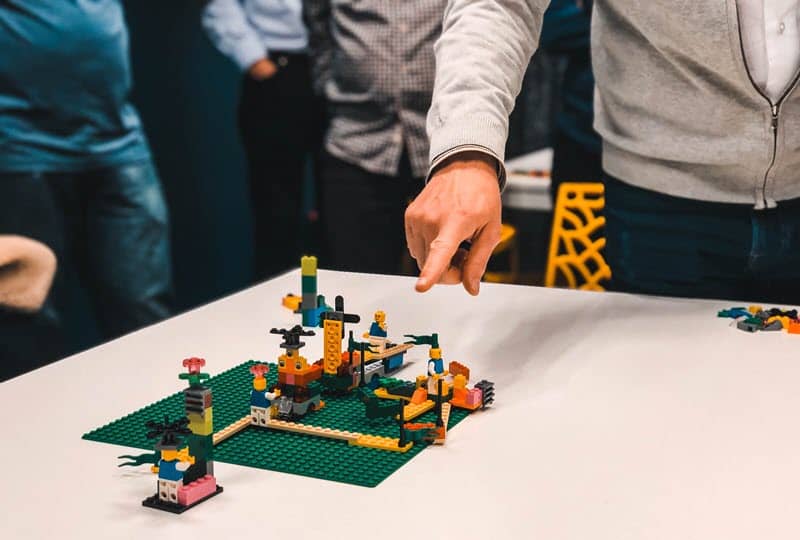 A group of people gathered around a table using LEGO® bricks to solve a problem.