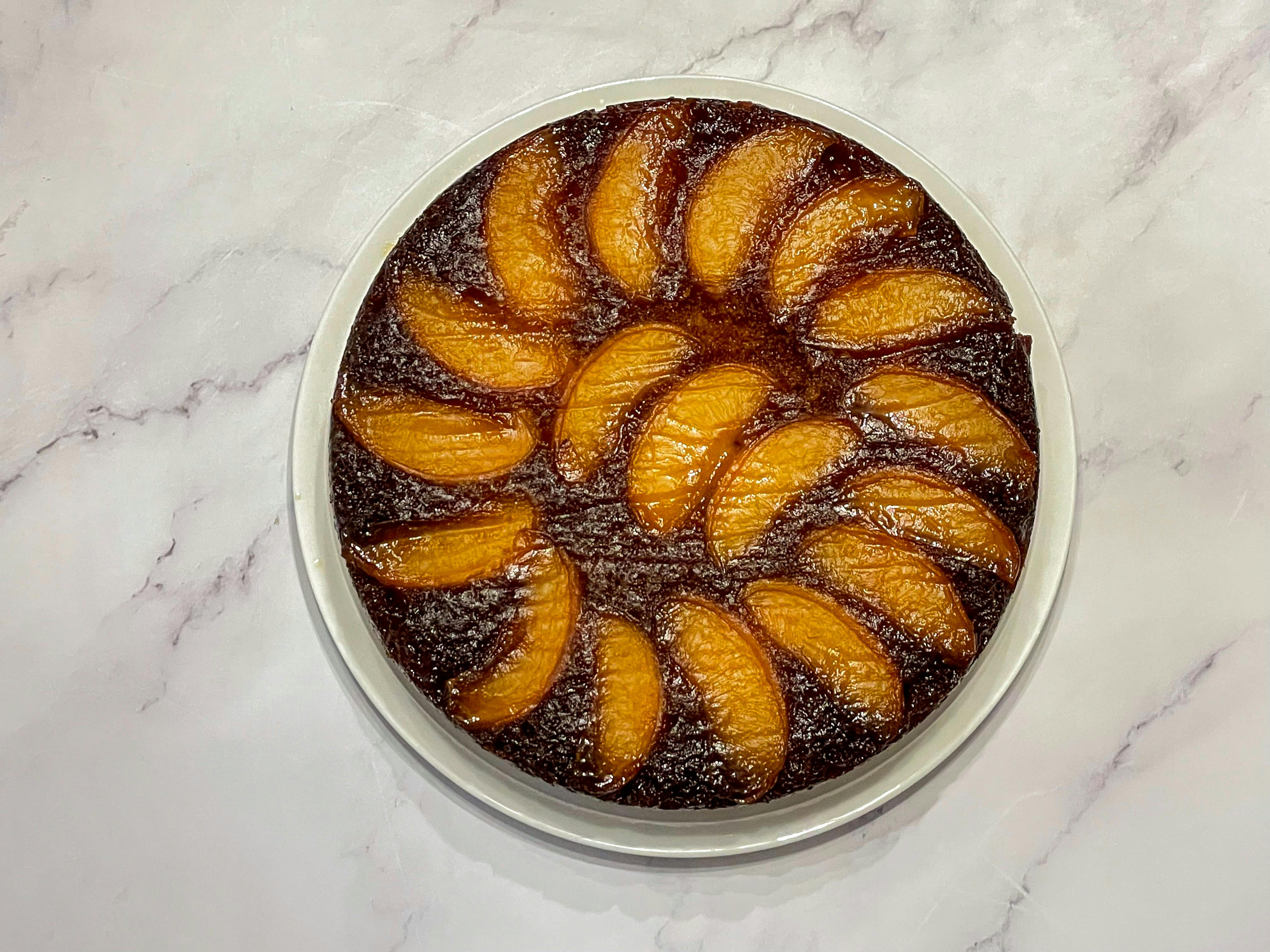 Peach upside down cake on a white marble surface