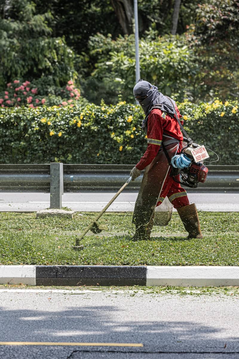 A worker is trimming grass with a weed whacker.