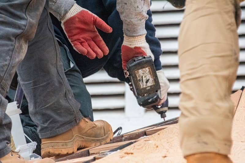 Workers are using a drill on a roof.