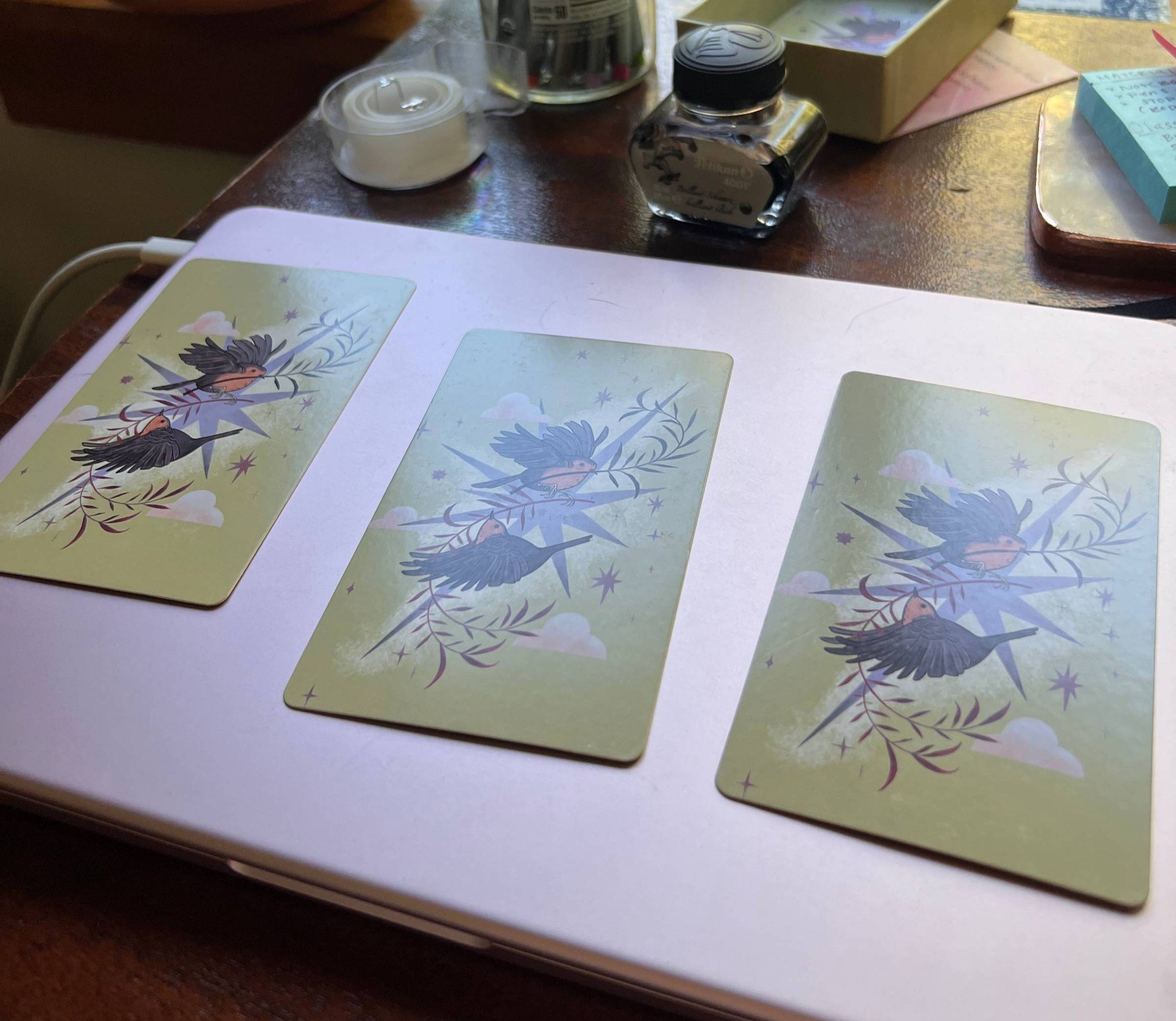 Three oracle cards face down atop a pink laptop