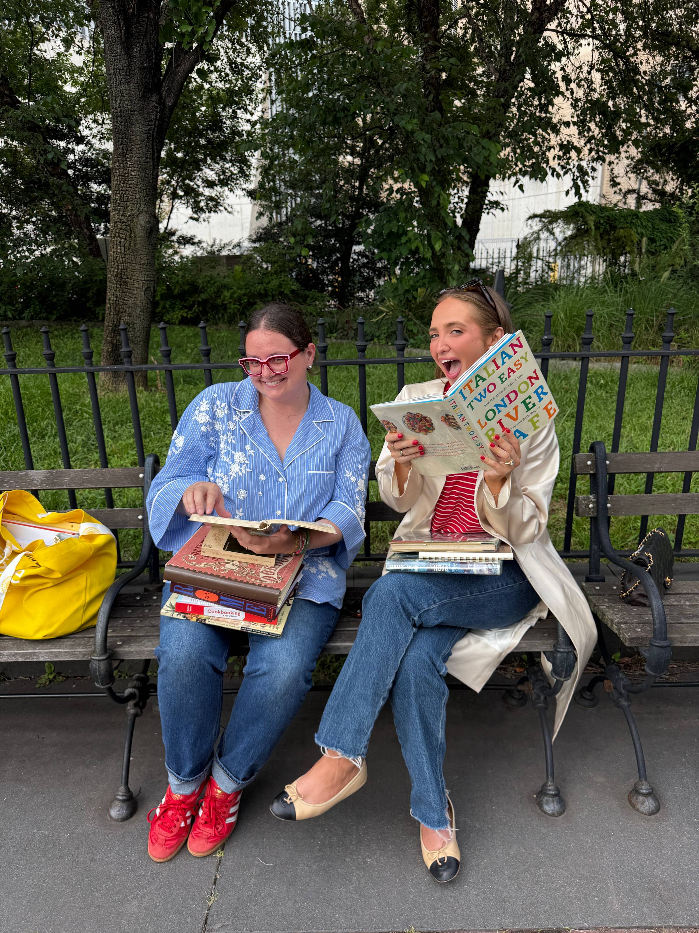 Kenzie Elizabeth and Krissy Downey reading cookbooks on a bench in New York City