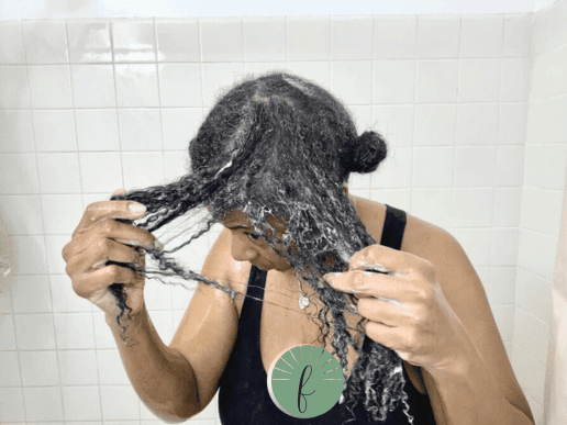 woman with curly hair detangling with conditioner in the shower