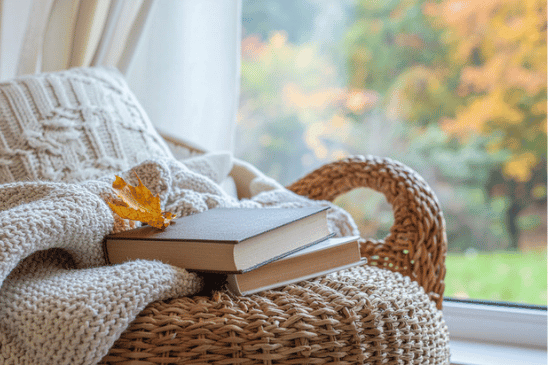 cozy corner with a Bible on a woven chair by a window with a fall scene