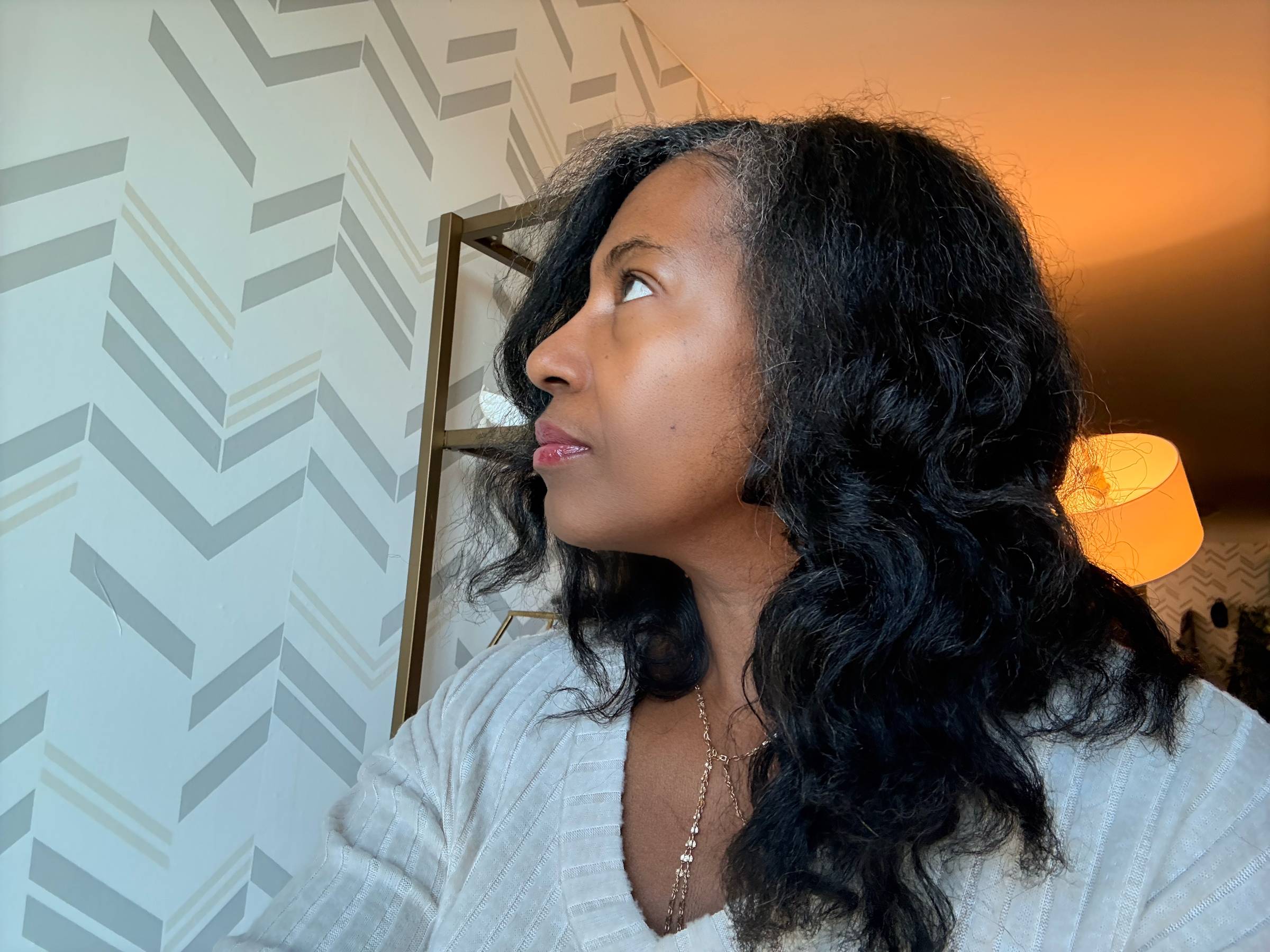 black woman with straightened natural hair in a bantu knot out looking contemplatingly up