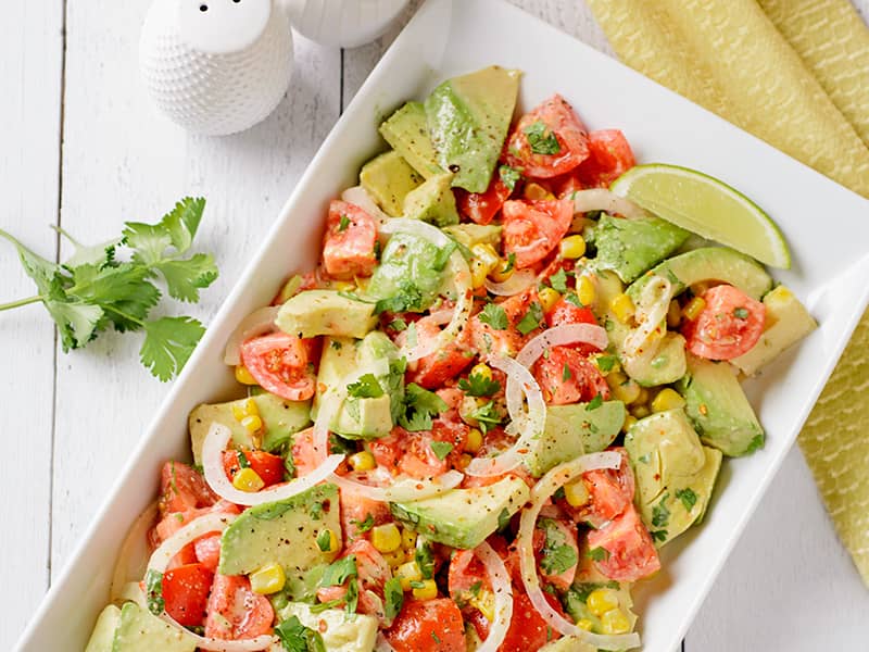Avocado and tomato salad with creamy lime dressing on a serving platter.