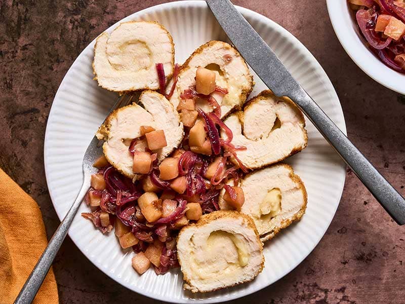 An overhead view of chicken roulade with Gruyere served with caramelized apples and onions.