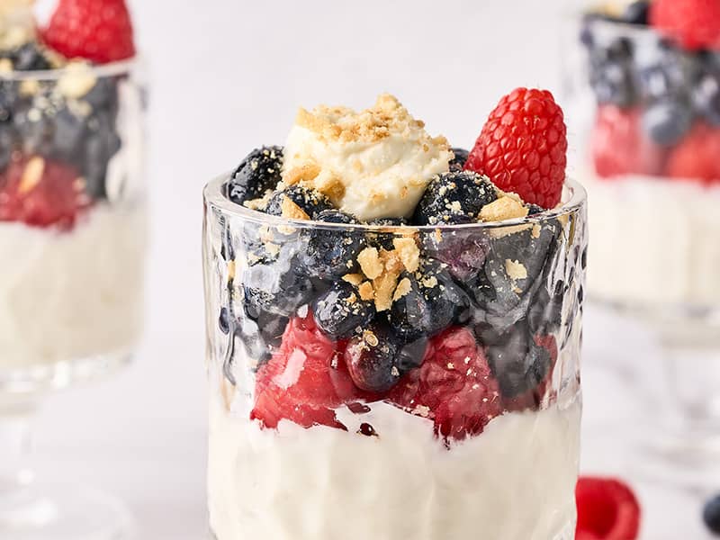 No-bake cheesecake parfaits topped with fresh blueberries and raspberries.