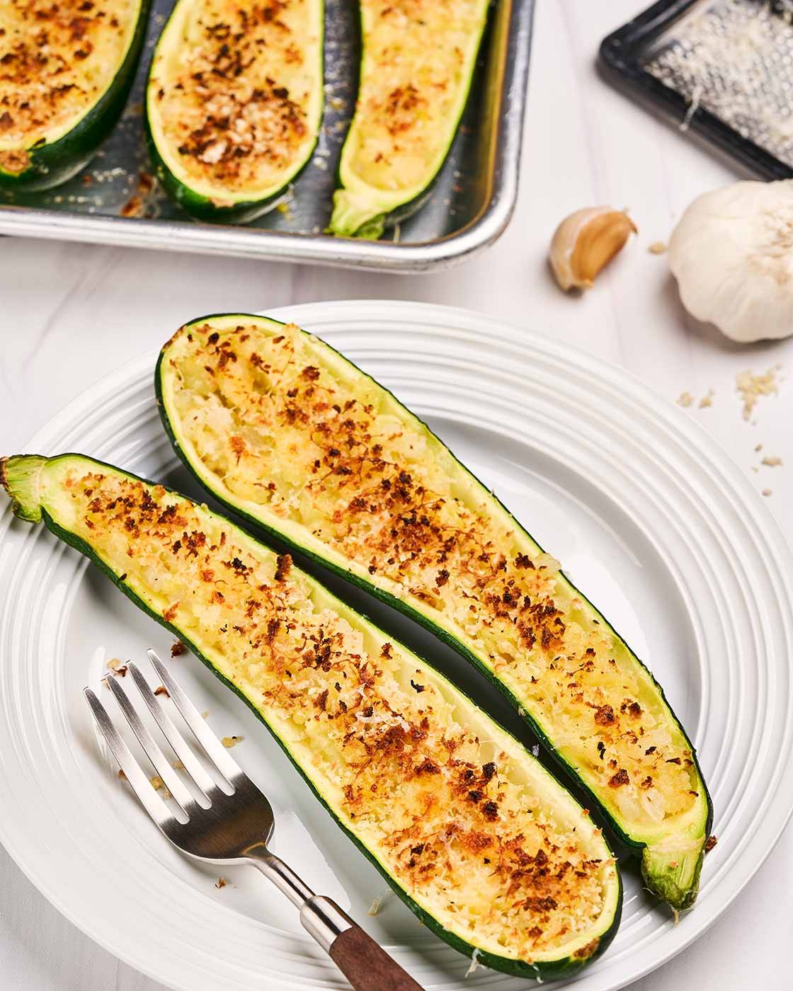 A plate with two zucchini boats stuffed with cheese, sautéed onions, and panko, baked until golden.
