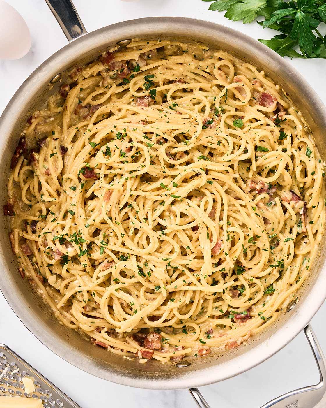 One-pot spaghetti carbonara with bacon, Parmesan, and parsley in a stainless skillet.
