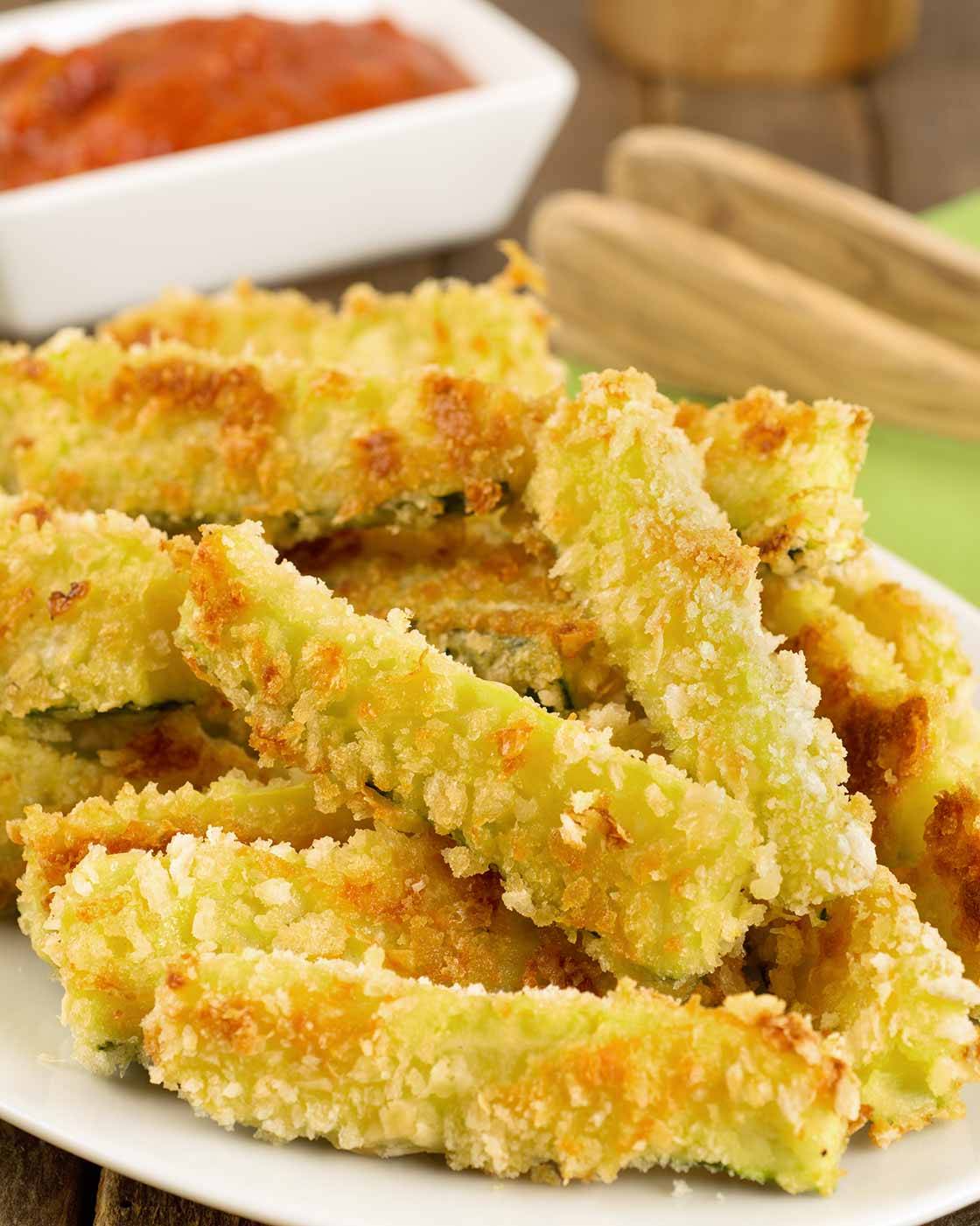 Crispy oven-fried zucchini sticks coated with panko and Parmesan cheese on a platter.