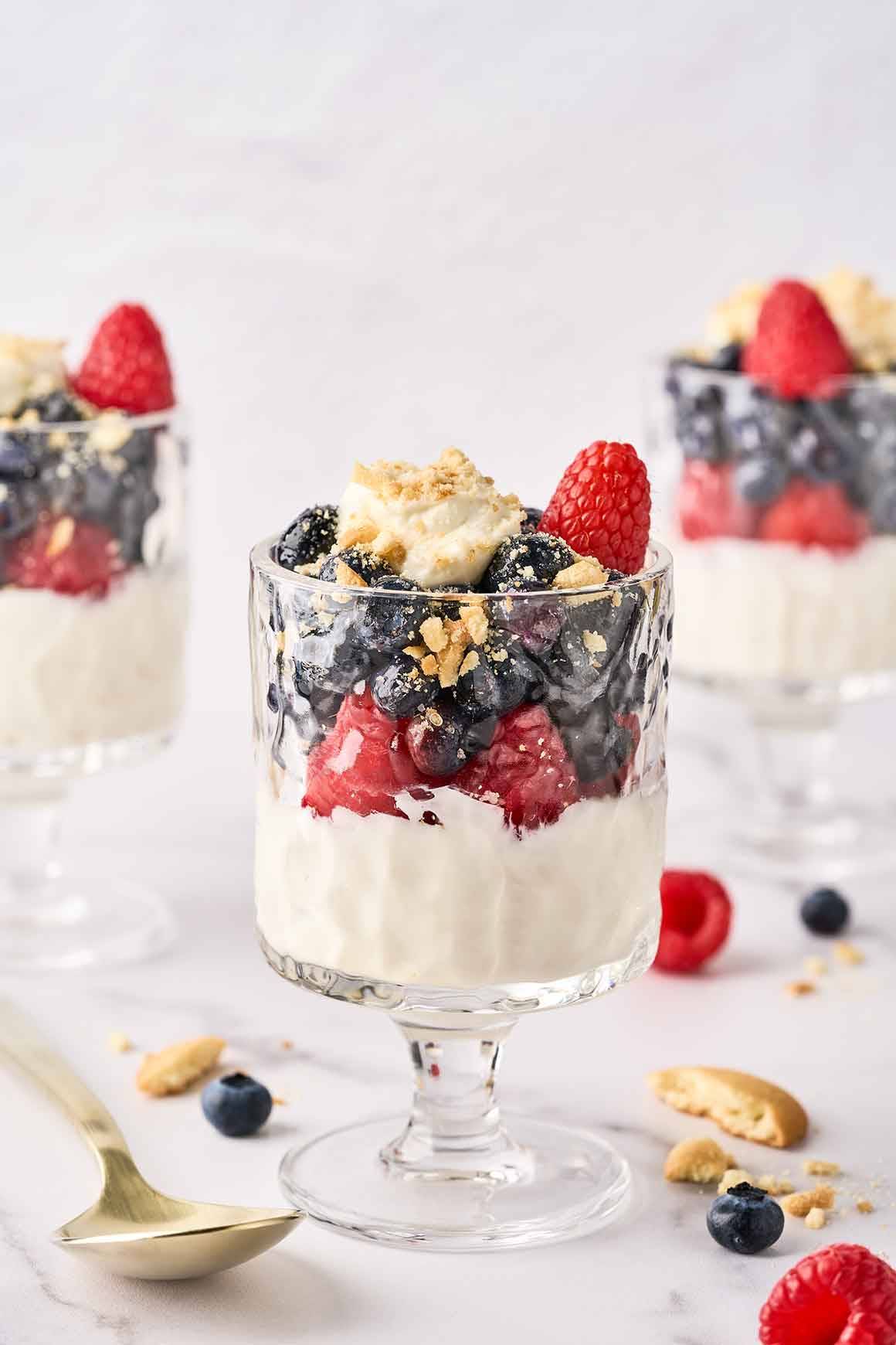 No-Bake cheesecake parfaits topped with fresh blueberries, raspberries, and vanilla wafer crumbs.
