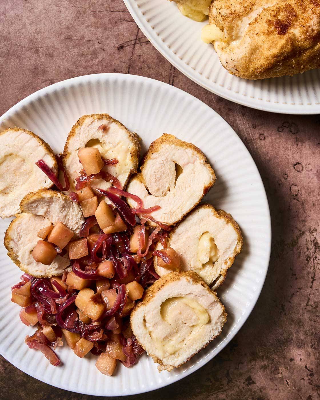 Sliced chicken roulade with Gruyere cheese filling and golden breadcrumb coating, served with caramelized apples and red onions.