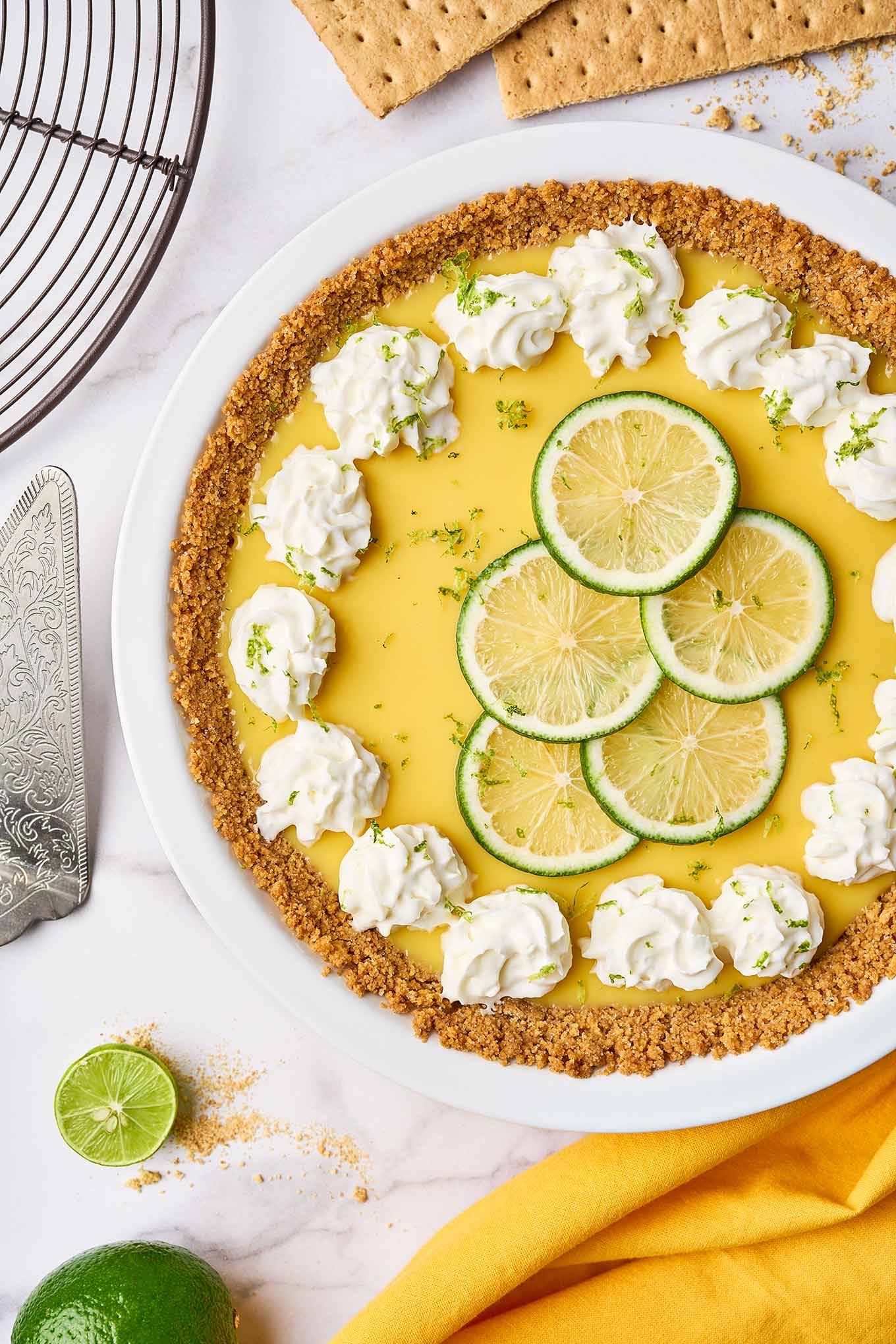Florida Key lime pie with graham cracker crust, topped with whipped cream and lime slices on a white serving plate.