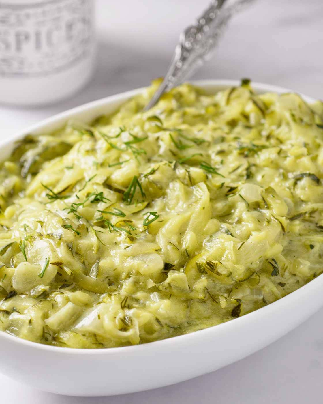 An oval serving bowl filled with creamy Hungarian summer squash with dill. 