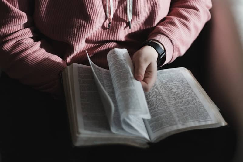 person in red and white striped long sleeve shirt holding book