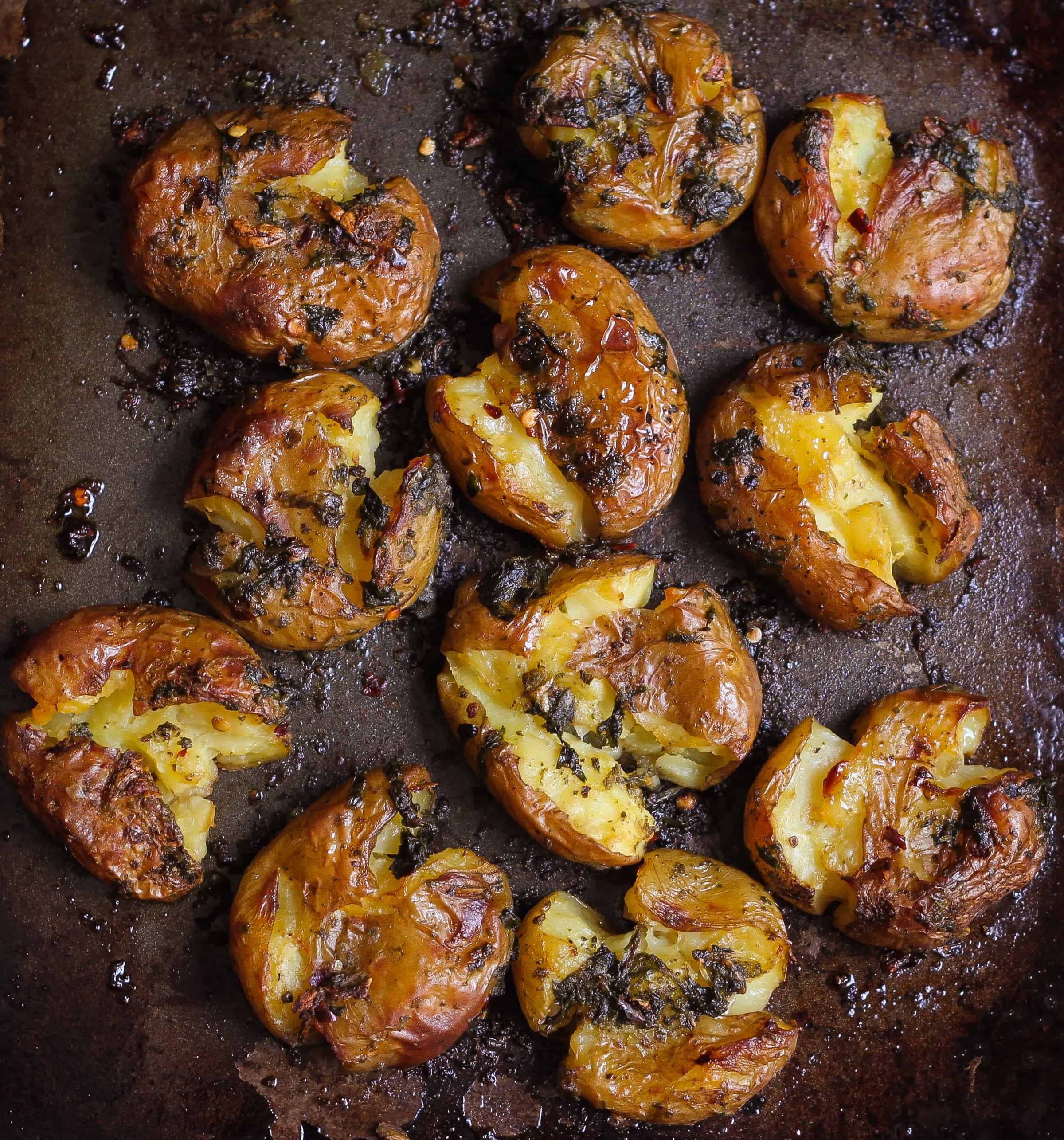 crispy smashed potatoes on a black baking tray.