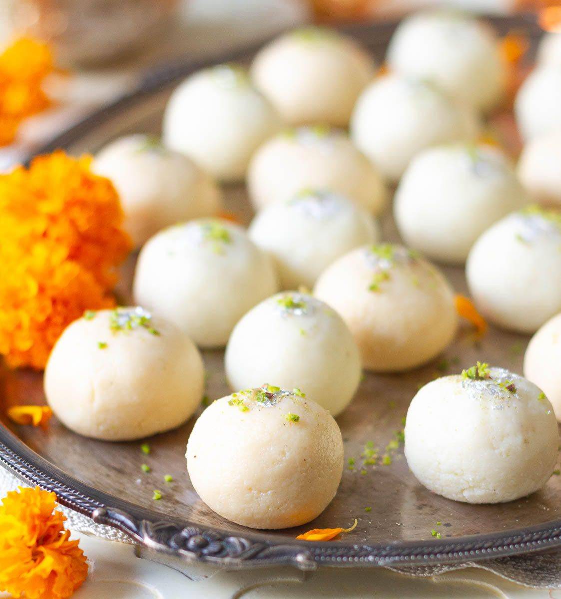 A platter full of laddoos with marigold flowers.