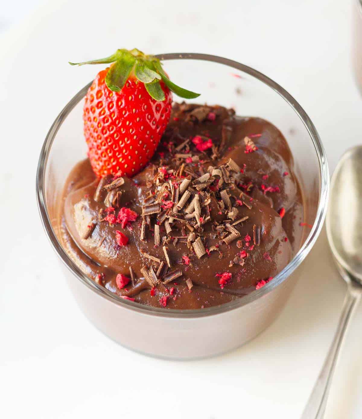 Chocolate mousse with chocolate shavings and strawberry in a cup.