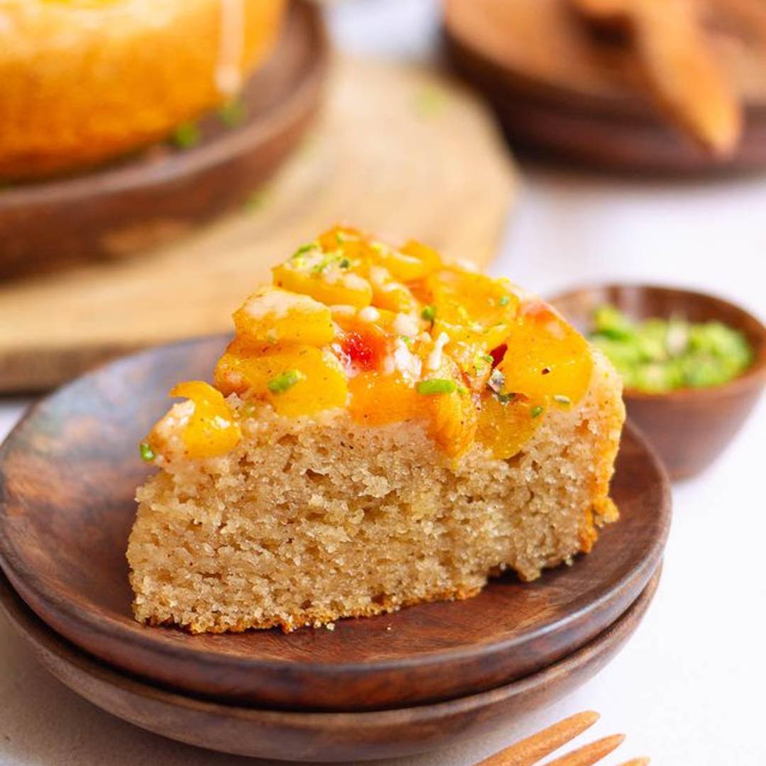 A slice of peach cobbler cake on a wooden plate.