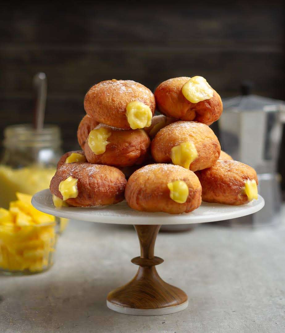 A cake stand stacked with mango filled donuts.