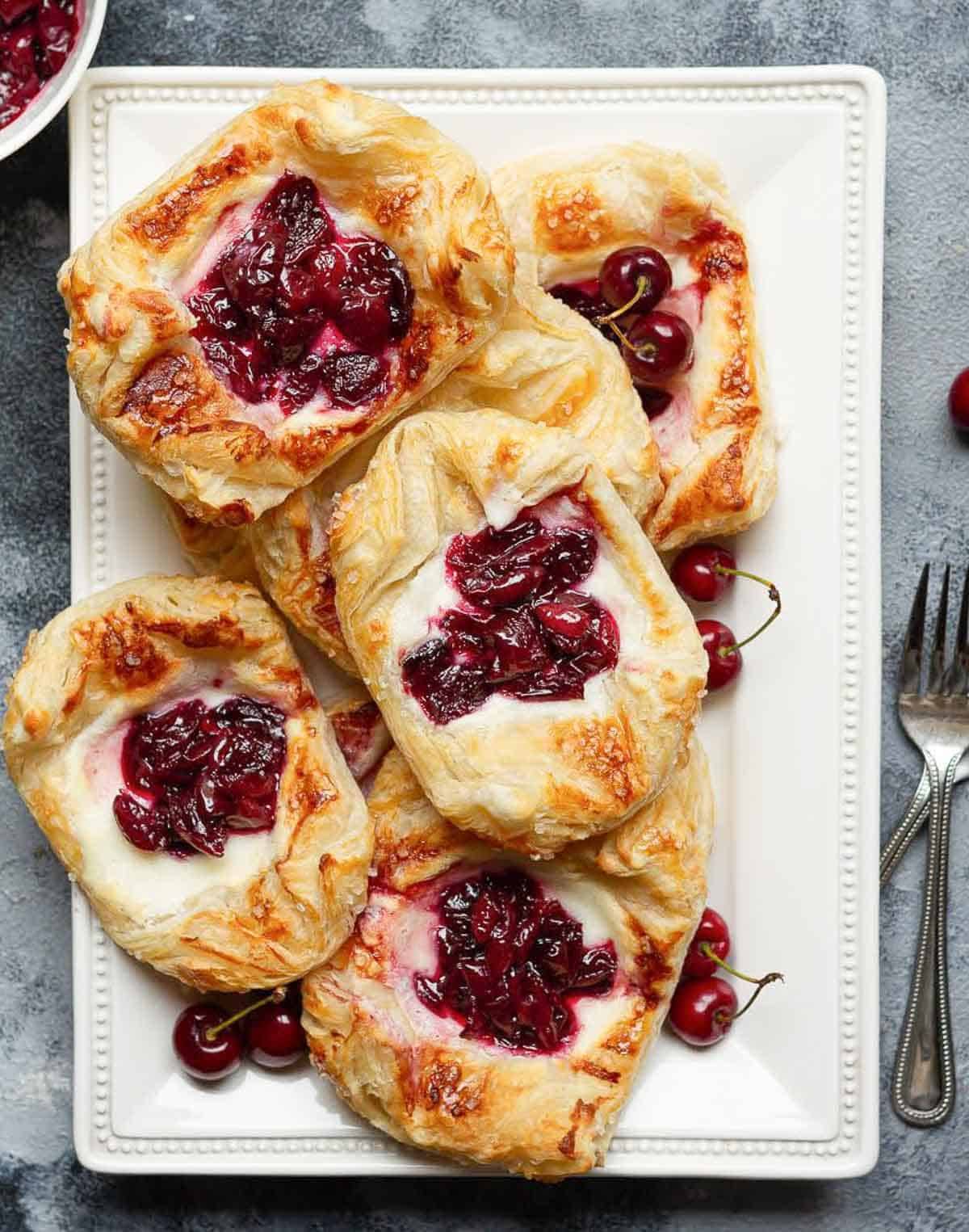 Small cherry tarts on a white platter.