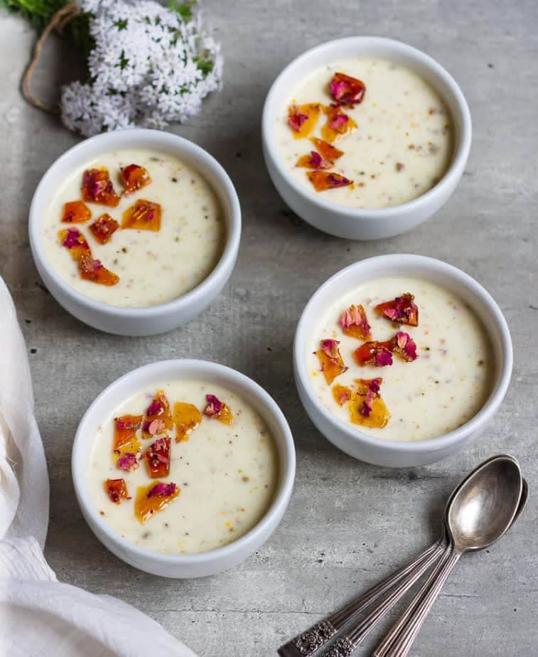 4 bowls of baked yogurt with spoons and flowers on the side.