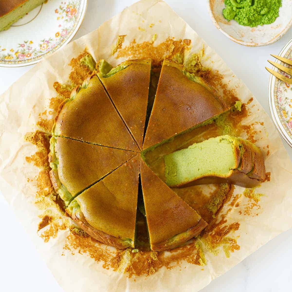 Sliced matcha cheesecake on parchment paper with one slice kept sideways.