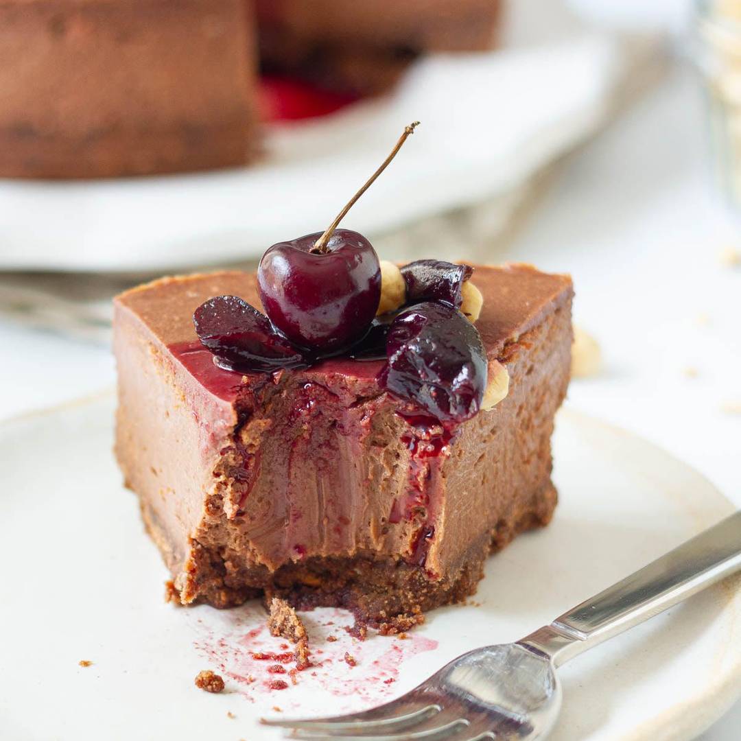 A bite taken from a slice of cheesecake on a plate with a fork.