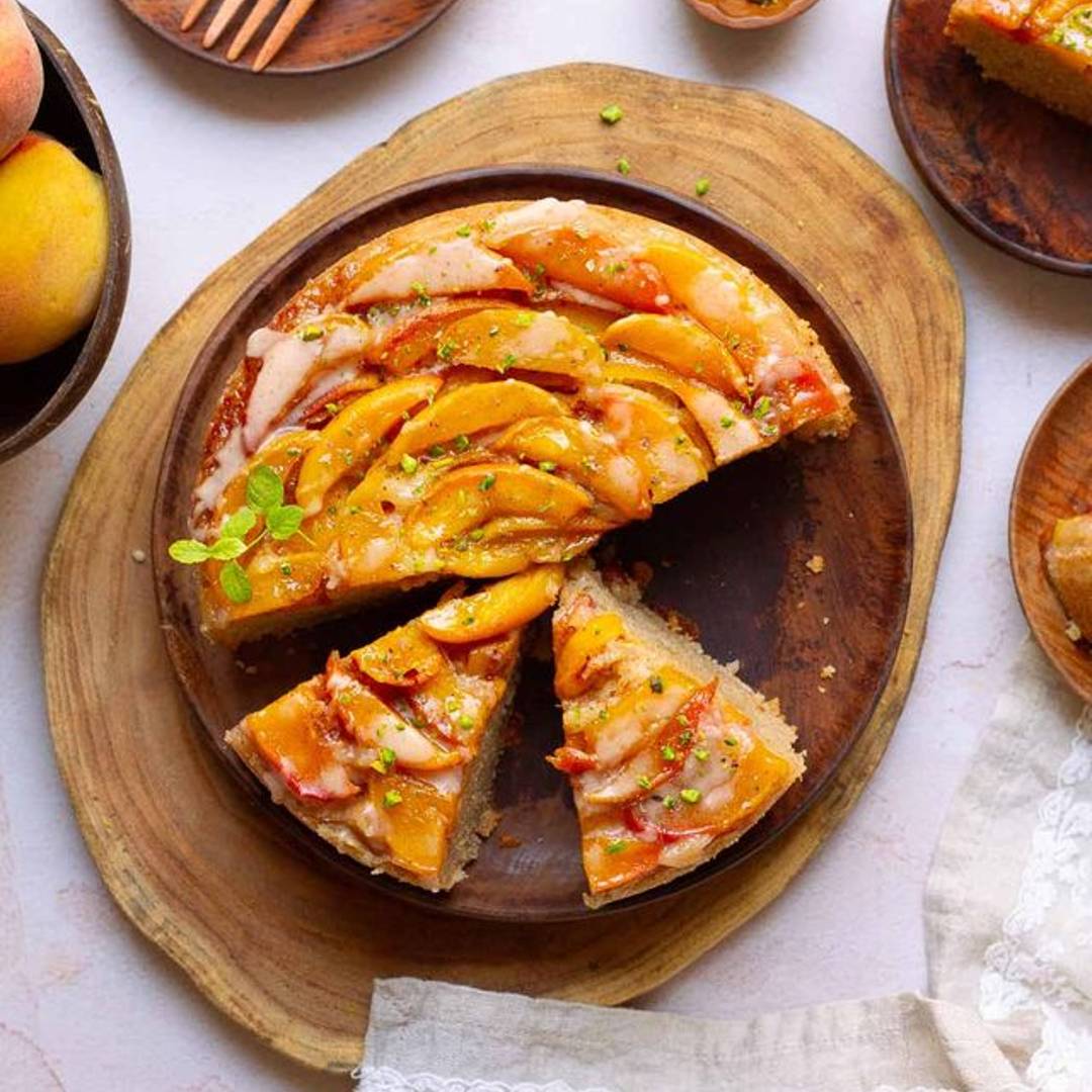 Sliced peach cobbler cake on a wooden platter.