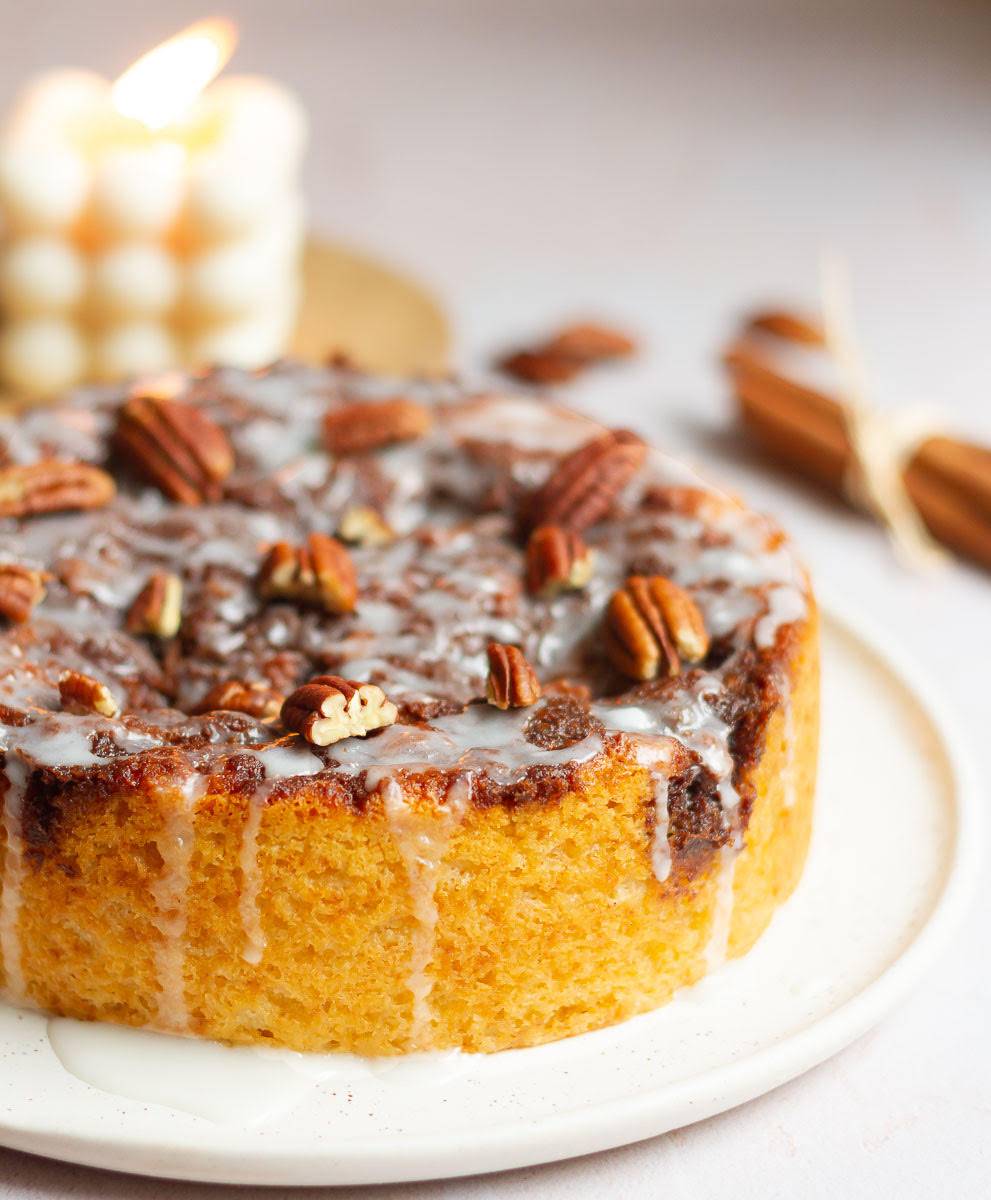 Cinnamon roll cake on a platter with a candle in the background.