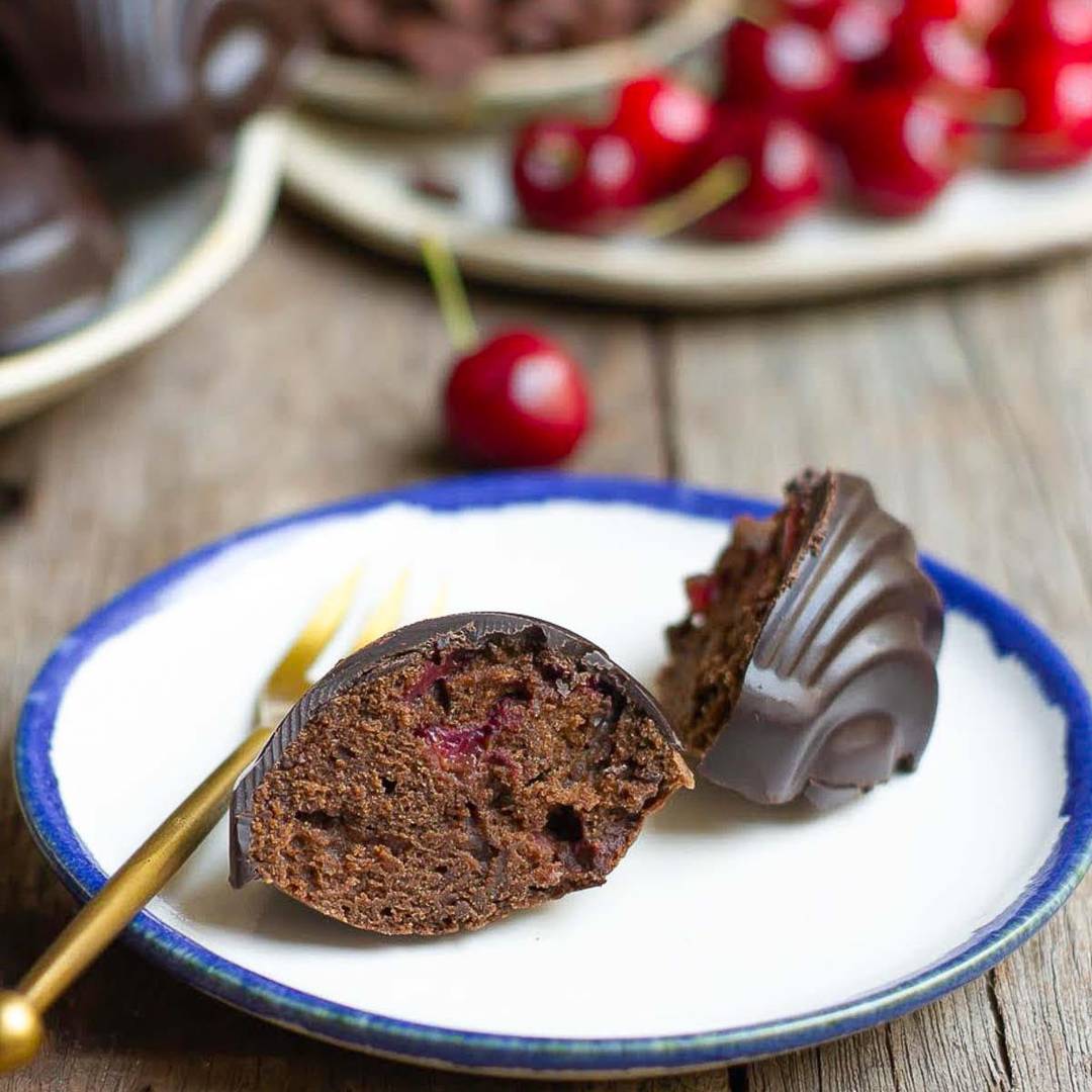 One chocolate cherry madeleine on a plate cut into half.