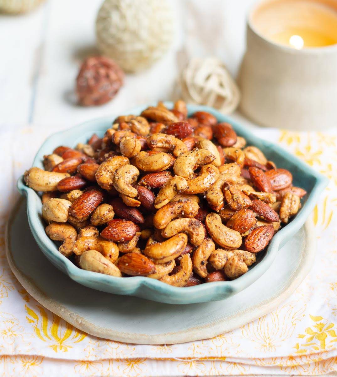 A bowl of nuts with a candle in the background.