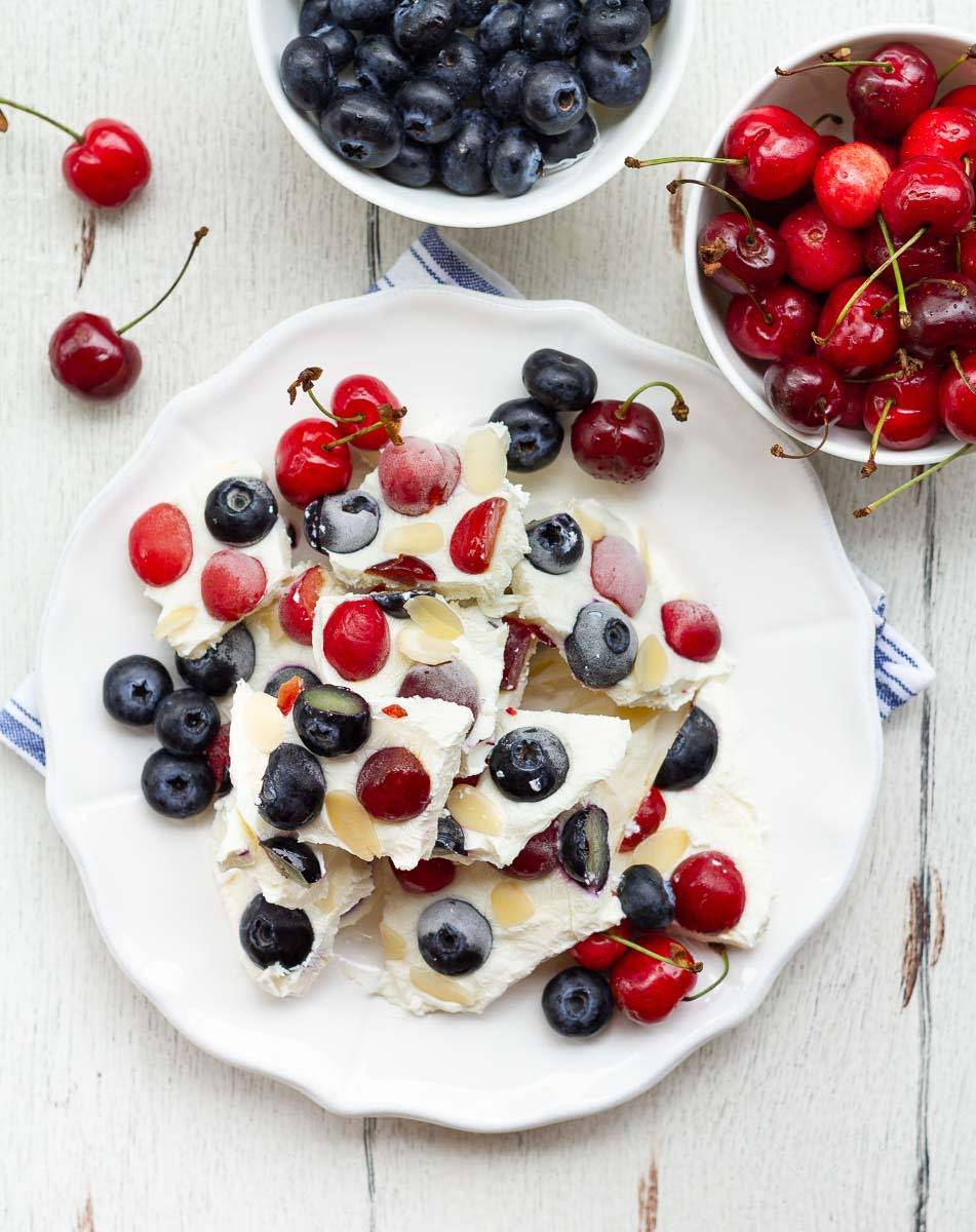 Pieces of frozen yogurt with berries stacked on a white plate.