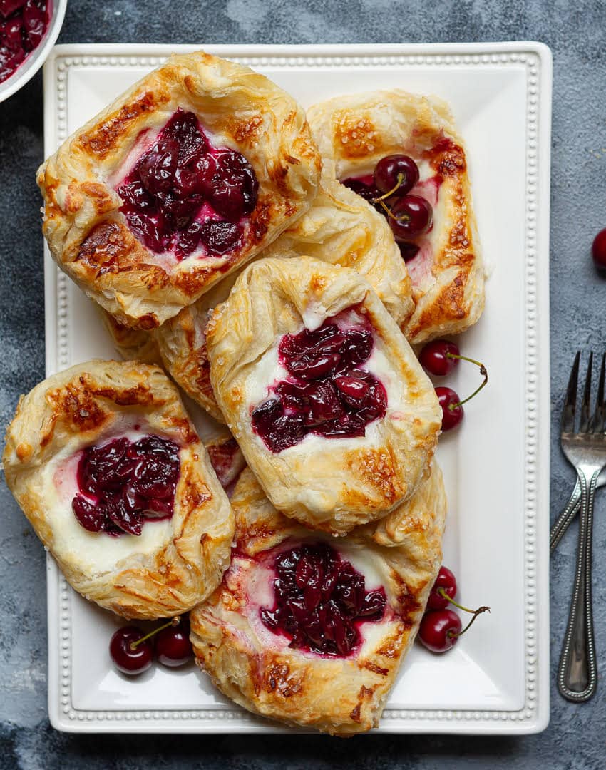 cherry puff pastry tarts on a white platter.