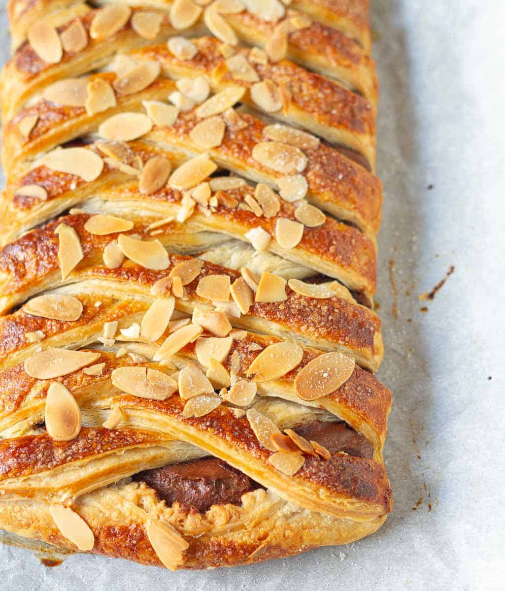 Puff pastry braid with chocolate on parchment paper.