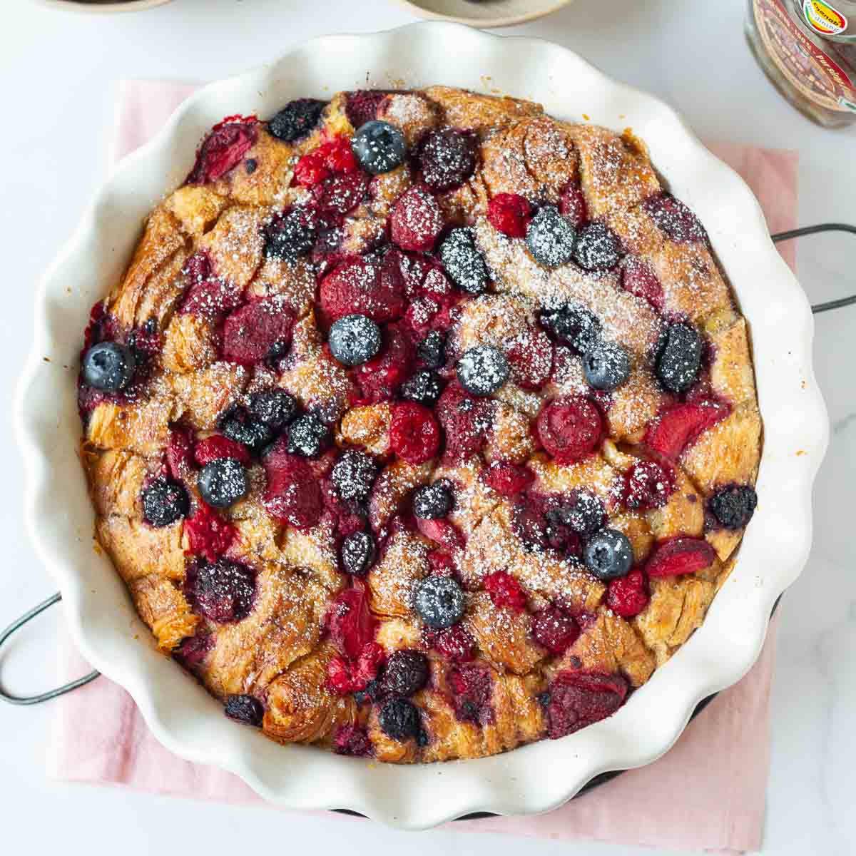 A croissant bake with berries on top in a baking dish.