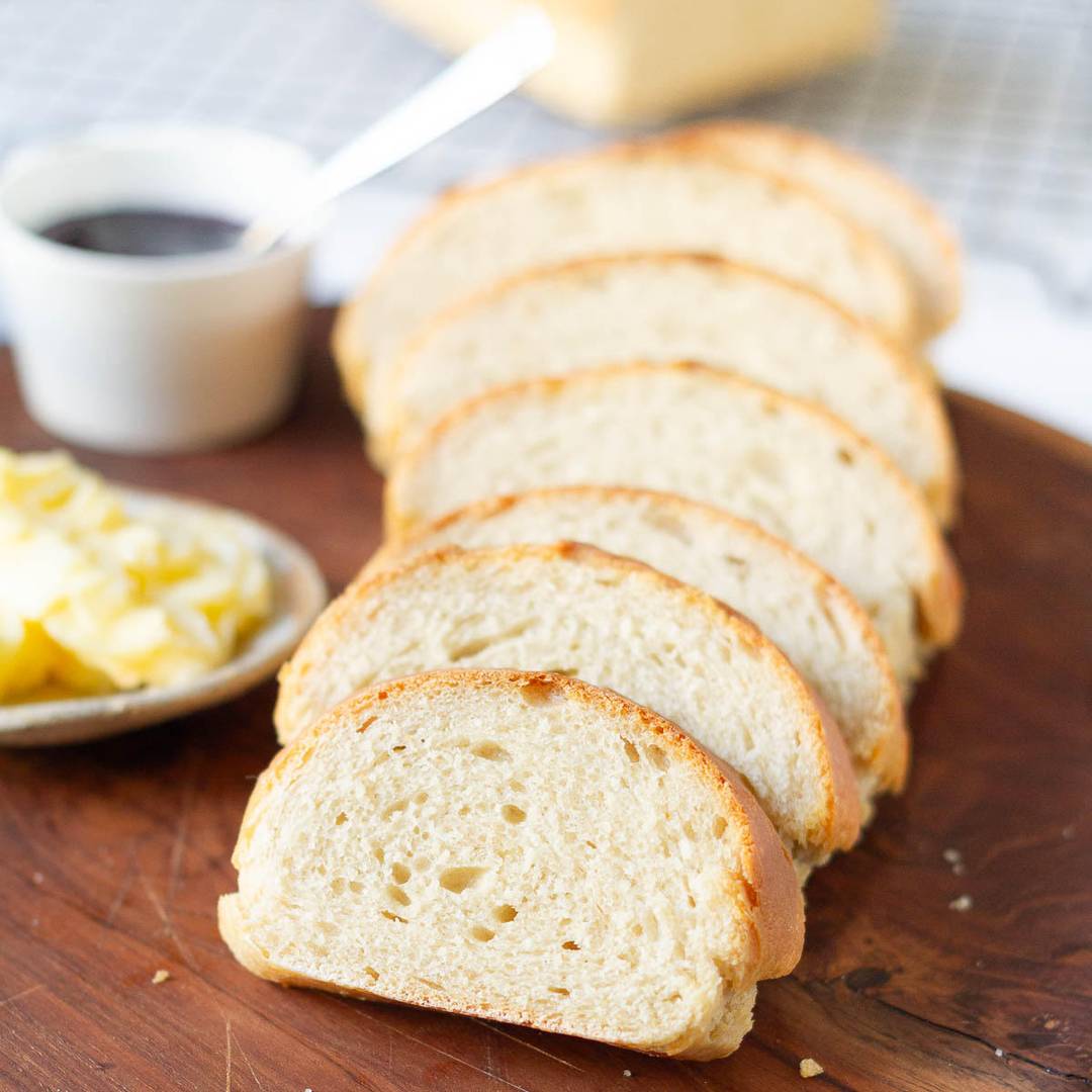 Sliced bread with butter and jam on a board.