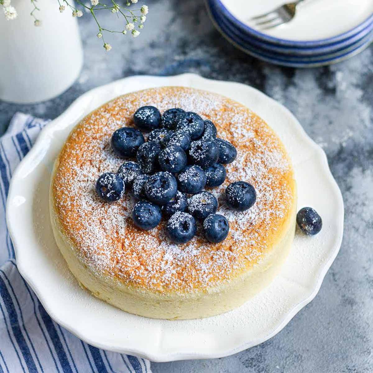 Japanese cheesecake topped with blueberries on a white platter.