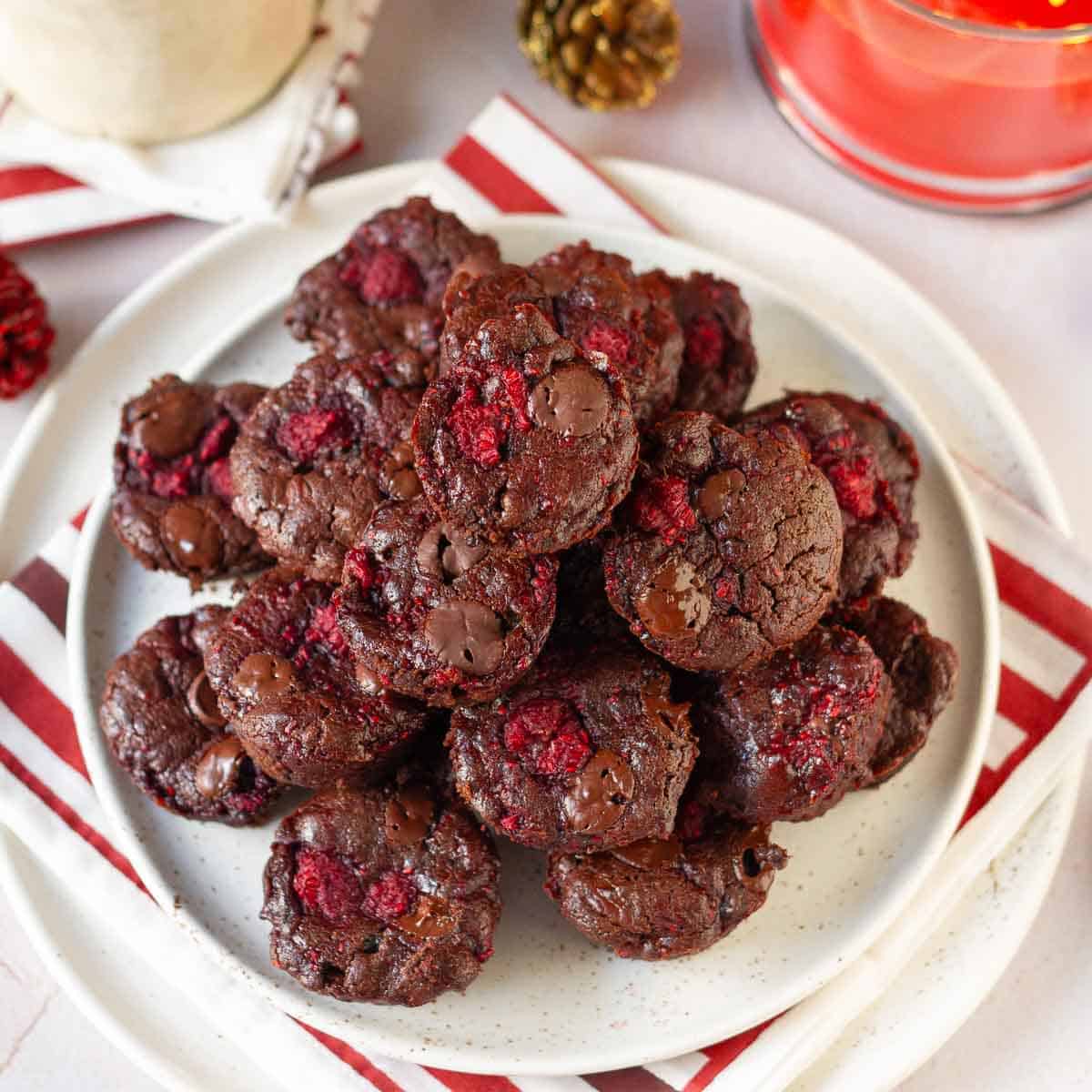 Mini brownies with raspberries stacked on a plate.