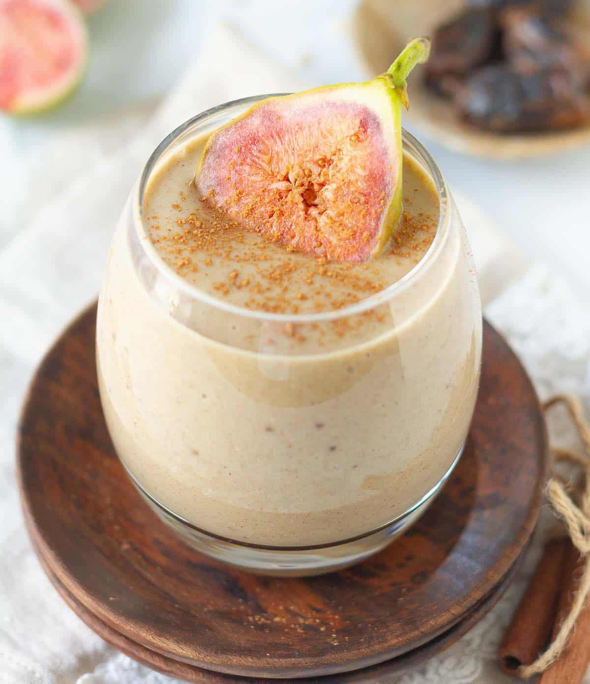 A glass of smoothie with a fig slice on top.