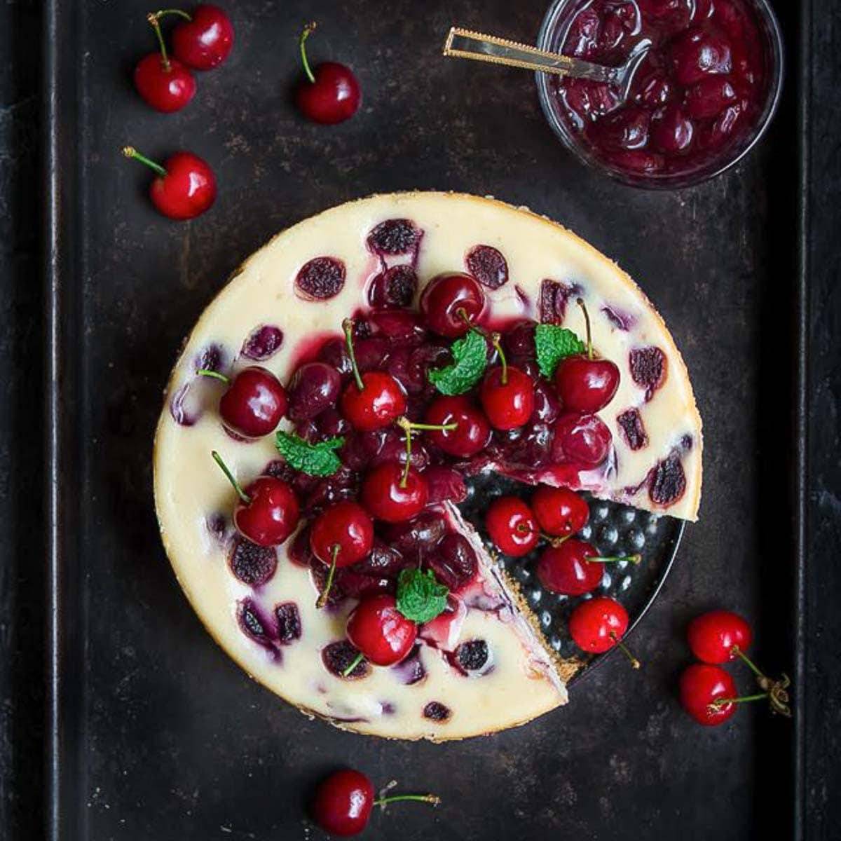 Cherry cheesecake topped with cherries with cherry sauce in a bowl.