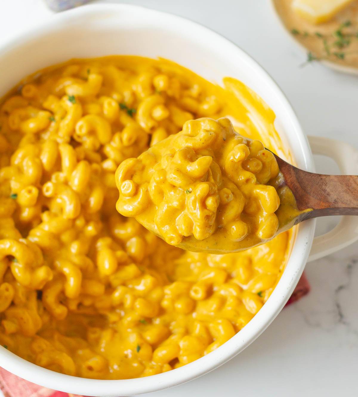 A spoonful of pumpkin mac and cheese over a pot.