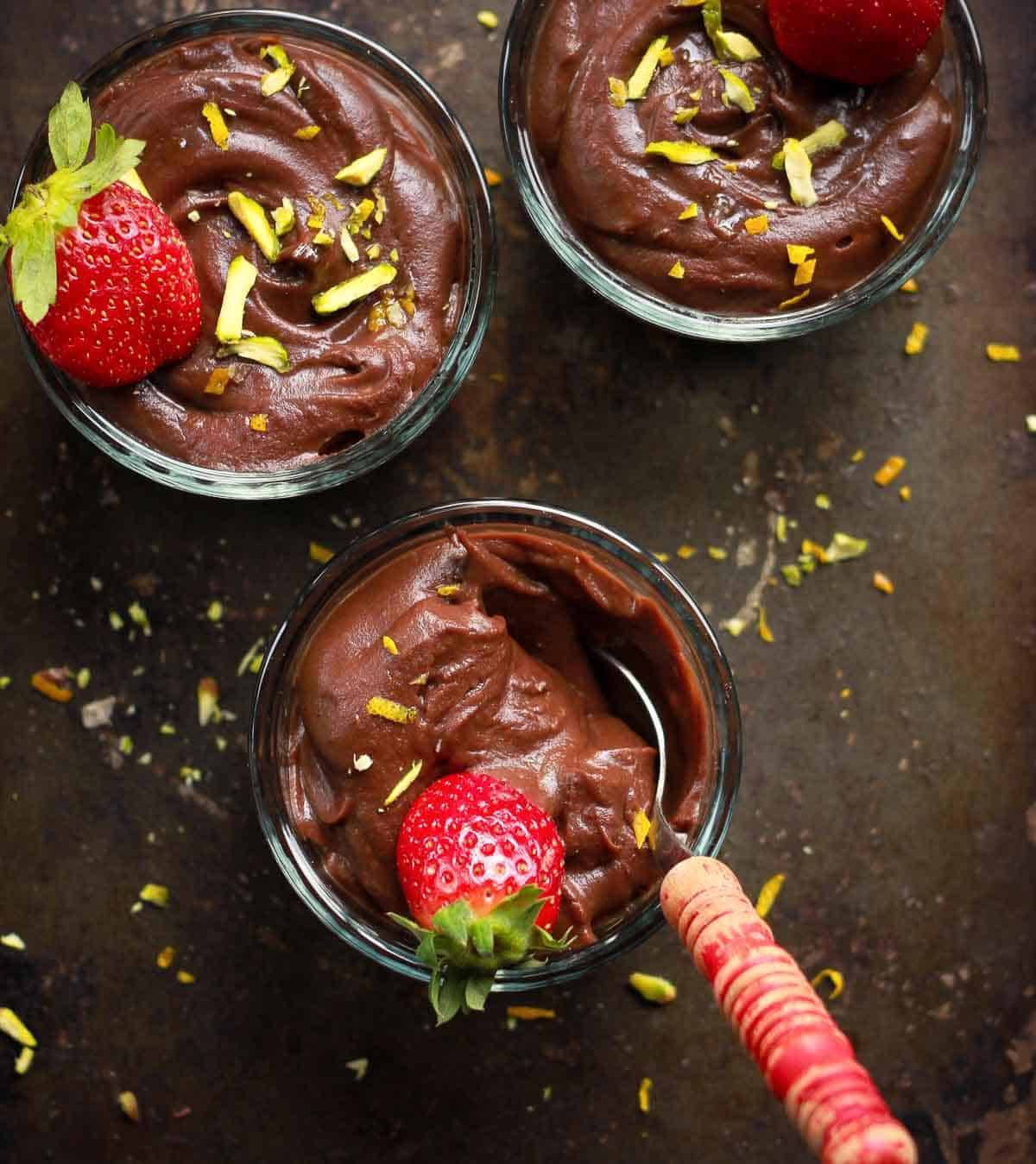 3 cups of chocolate pudding topped with strawberries.