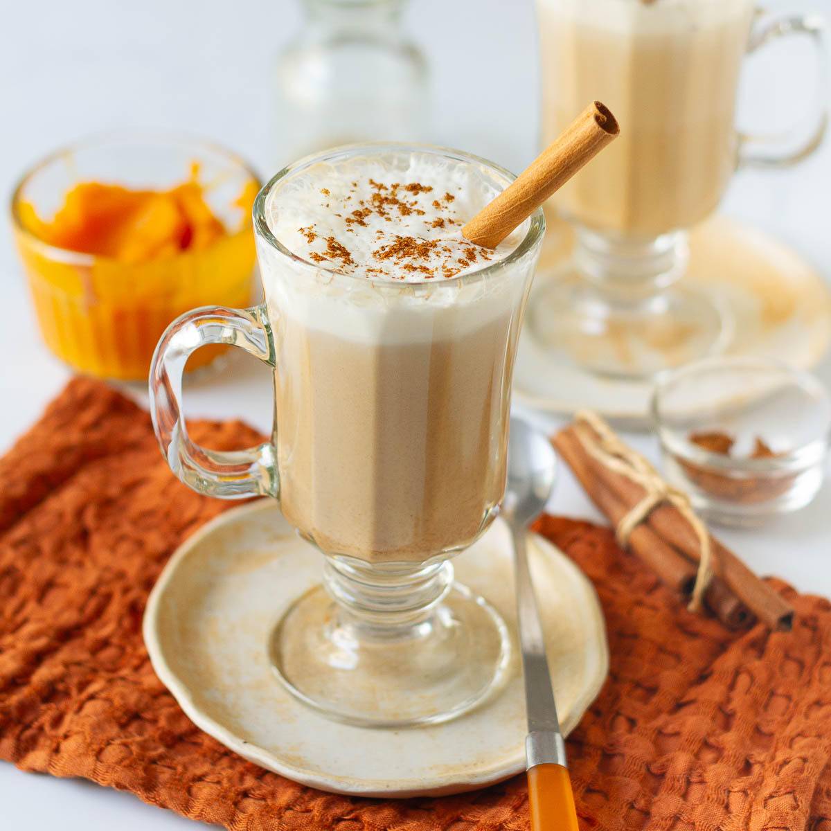 Pumpkin spice latte in a mug topped with milk froth, whipped cream, and cinnamon.