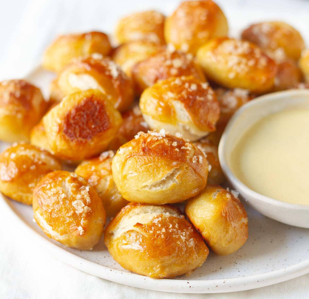A platter full of pretzel bites with a bowl of dip.