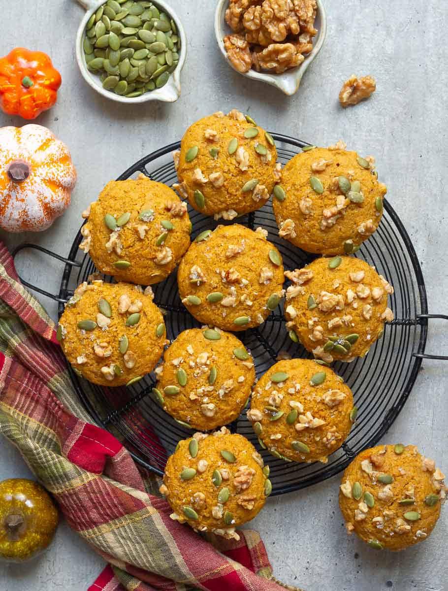 Pumpkin muffins on a wire rack with a napkin and decorations on the side.