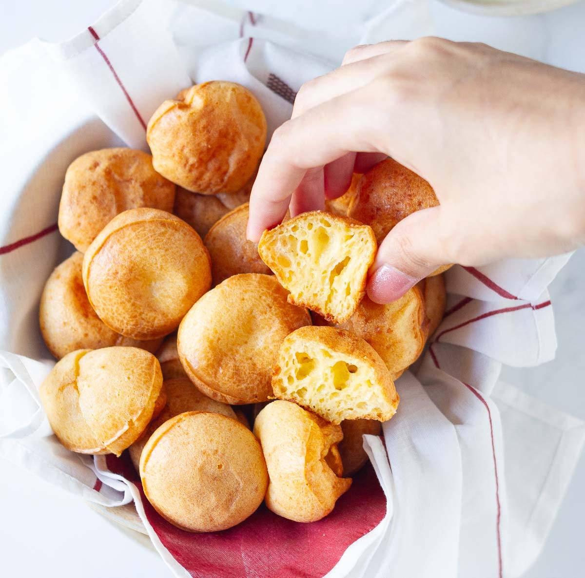 A hand picking up half a bread from a bowl of breads.