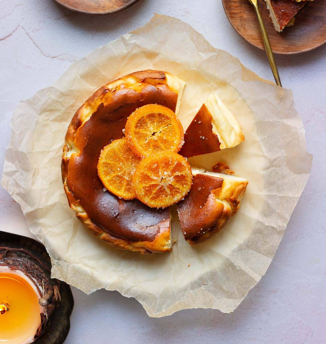 Orange basque cheesecake with candied oranges on parchment paper.