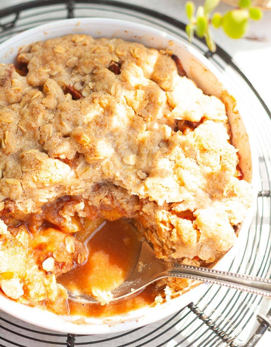 Apple crisp in a baking dish with a spoon.